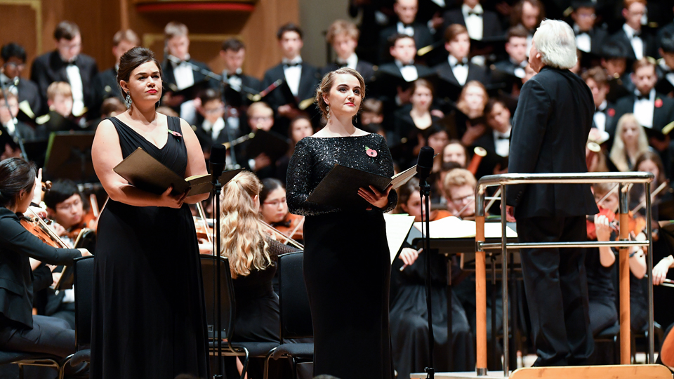 Two RCM singers in performance with an orchestra and choir